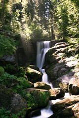 Wasserfall im Wald bei durchbrechendem Sonnenlicht