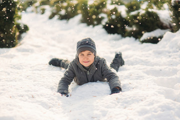 Fototapeta na wymiar A boy in winter clothes jumps into the snow