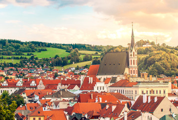 Obraz premium Cesky Krumlov, UNESCO, Czech Republic. Sunset aerial view of the old town pier architecture and St. Vitus Church with red rooftops and houses.