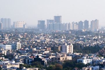 Obraz premium Aerial shot of cityscape with houses, offices and skyscrapers in the distance. Shows the crowded and messy nature of metro cities like Noida, Delhi, gurgaon, lucknow, jaipur, banaglore. Shows the fog