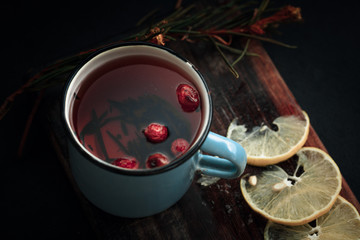 Treating cold. Hot tea with lemon and berries stands on white wooden table