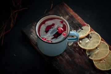 Treating cold. Hot tea with lemon and berries stands on white wooden table