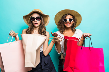 Portrait of two young sexy stylish smiling brunette women holding shopping bags. Girls dressed in...
