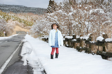 Beautiful little girl mixed race Japanese and Brazilian smiling at the roadside after snowfall. Shizuoka Prefecture, Japan. Winter of February 2011.