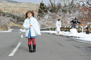 Fototapeta na wymiar Pretty little girl of mixed race Japanese and Brazilian with his left hand inside a plastic bag preparing to play with snow. Shizuoka Prefecture, Japan. Winter of February 2011. Horizontal shot.