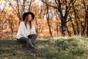 Fototapeta premium beautiful woman sitting on grass on sunny autumn day.