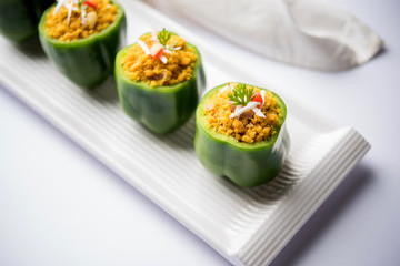 Stuffed capsicum or bharwa shimla mirchi is a popular Indian main course recipe. Served in a plate over moody background. Selective focus