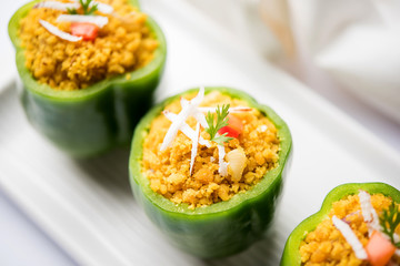 Stuffed capsicum or bharwa shimla mirchi is a popular Indian main course recipe. Served in a plate over moody background. Selective focus