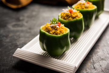 Stuffed capsicum or bharwa shimla mirchi is a popular Indian main course recipe. Served in a plate over moody background. Selective focus