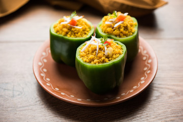 Stuffed capsicum or bharwa shimla mirchi is a popular Indian main course recipe. Served in a plate over moody background. Selective focus