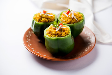 Stuffed capsicum or bharwa shimla mirchi is a popular Indian main course recipe. Served in a plate over moody background. Selective focus