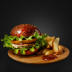 Appetizing burger on a wooden board against a dark background.