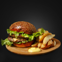 Appetizing burger on a wooden board against a dark background.