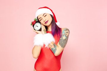 Girl with purple hair tips and tattoo on her arm dressed in red swimsuit, Santa's hat and white fur...