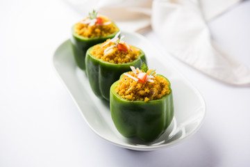 Stuffed capsicum or bharwa shimla mirchi is a popular Indian main course recipe. Served in a plate over moody background. Selective focus