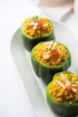 Stuffed capsicum or bharwa shimla mirchi is a popular Indian main course recipe. Served in a plate over moody background. Selective focus