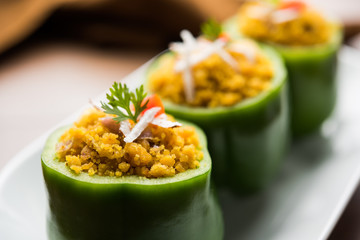 Stuffed capsicum or bharwa shimla mirchi is a popular Indian main course recipe. Served in a plate over moody background. Selective focus