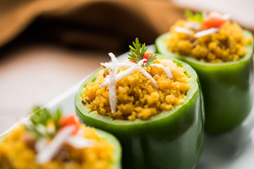Stuffed capsicum or bharwa shimla mirchi is a popular Indian main course recipe. Served in a plate over moody background. Selective focus