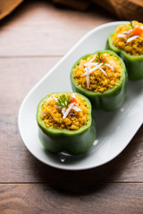 Stuffed capsicum or bharwa shimla mirchi is a popular Indian main course recipe. Served in a plate over moody background. Selective focus