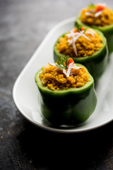 Stuffed capsicum or bharwa shimla mirchi is a popular Indian main course recipe. Served in a plate over moody background. Selective focus