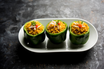 Stuffed capsicum or bharwa shimla mirchi is a popular Indian main course recipe. Served in a plate over moody background. Selective focus