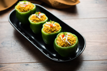 Stuffed capsicum or bharwa shimla mirchi is a popular Indian main course recipe. Served in a plate over moody background. Selective focus