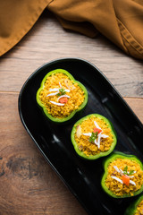 Stuffed capsicum or bharwa shimla mirchi is a popular Indian main course recipe. Served in a plate over moody background. Selective focus