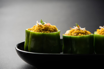 Stuffed capsicum or bharwa shimla mirchi is a popular Indian main course recipe. Served in a plate over moody background. Selective focus