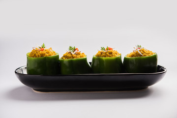 Stuffed capsicum or bharwa shimla mirchi is a popular Indian main course recipe. Served in a plate over moody background. Selective focus
