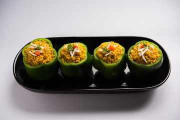 Stuffed capsicum or bharwa shimla mirchi is a popular Indian main course recipe. Served in a plate over moody background. Selective focus