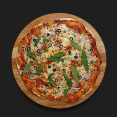 Appetizing pizza on a wooden board on a dark background. Classic feed.