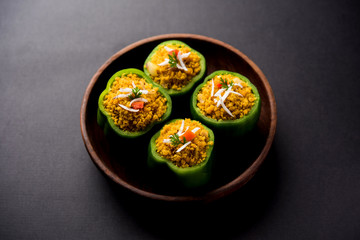 Stuffed capsicum or bharwa shimla mirchi is a popular Indian main course recipe. Served in a plate over moody background. Selective focus