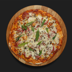 Appetizing pizza on a wooden board on a dark background. Classic feed.