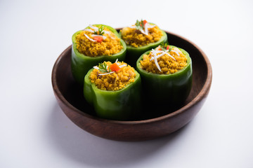 Stuffed capsicum or bharwa shimla mirchi is a popular Indian main course recipe. Served in a plate over moody background. Selective focus