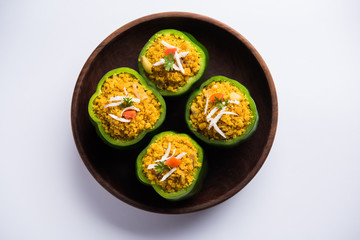 Stuffed capsicum or bharwa shimla mirchi is a popular Indian main course recipe. Served in a plate over moody background. Selective focus