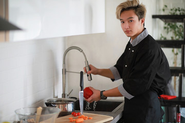 Asian cook in the kitchen prepares food in a cook suit