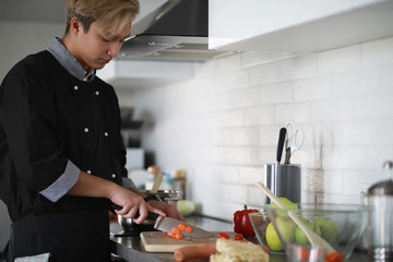 Asian cook in the kitchen prepares food in a cook suit