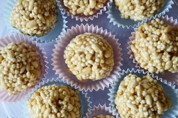 Closeup homemade cones made of puffed cereals, mainly rice and millet groats with fudge candy in colorful cupcake wrappers with blurred background