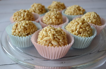 Closeup homemade cones made of puffed cereals, mainly rice and millet groats with fudge candy in colorful cupcake wrappers with blurred background