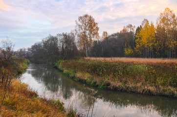 Foggy autumn landscape with small forest river.Windless calm weather.Autumn morning.