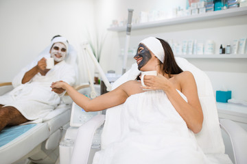 Young couple together receiving facial mask with rejuvenating effects in spa beauty salon.