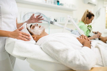 Obraz na płótnie Canvas Facial beauty treatment of good looking man with oxygen mask at cosmetic beauty salon.