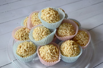 Closeup homemade cones made of puffed cereals, mainly rice and millet groats with fudge candy in colorful cupcake wrappers with blurred background