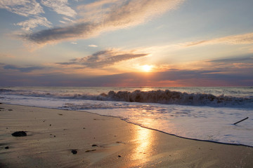 Foamy wave at the sunset sandy beach