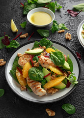 Grilled chicken with orange and avocado salad on rustic background