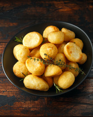 Roast golden potatoes seasoned with salt, garlic, rosemary and thyme on rustic wooden background