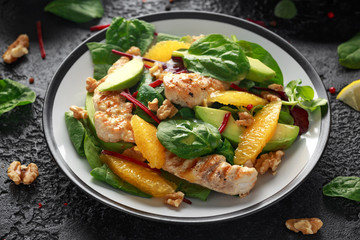 Grilled chicken with orange and avocado salad on rustic background