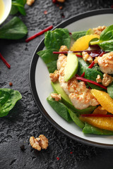 Grilled chicken with orange and avocado salad on rustic background
