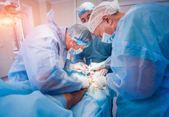 Process of trauma surgery operation. Group of surgeons in operating room with surgery equipment.