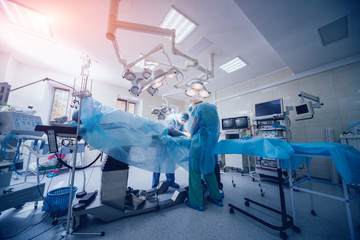 Process of trauma surgery operation. Group of surgeons in operating room with surgery equipment.